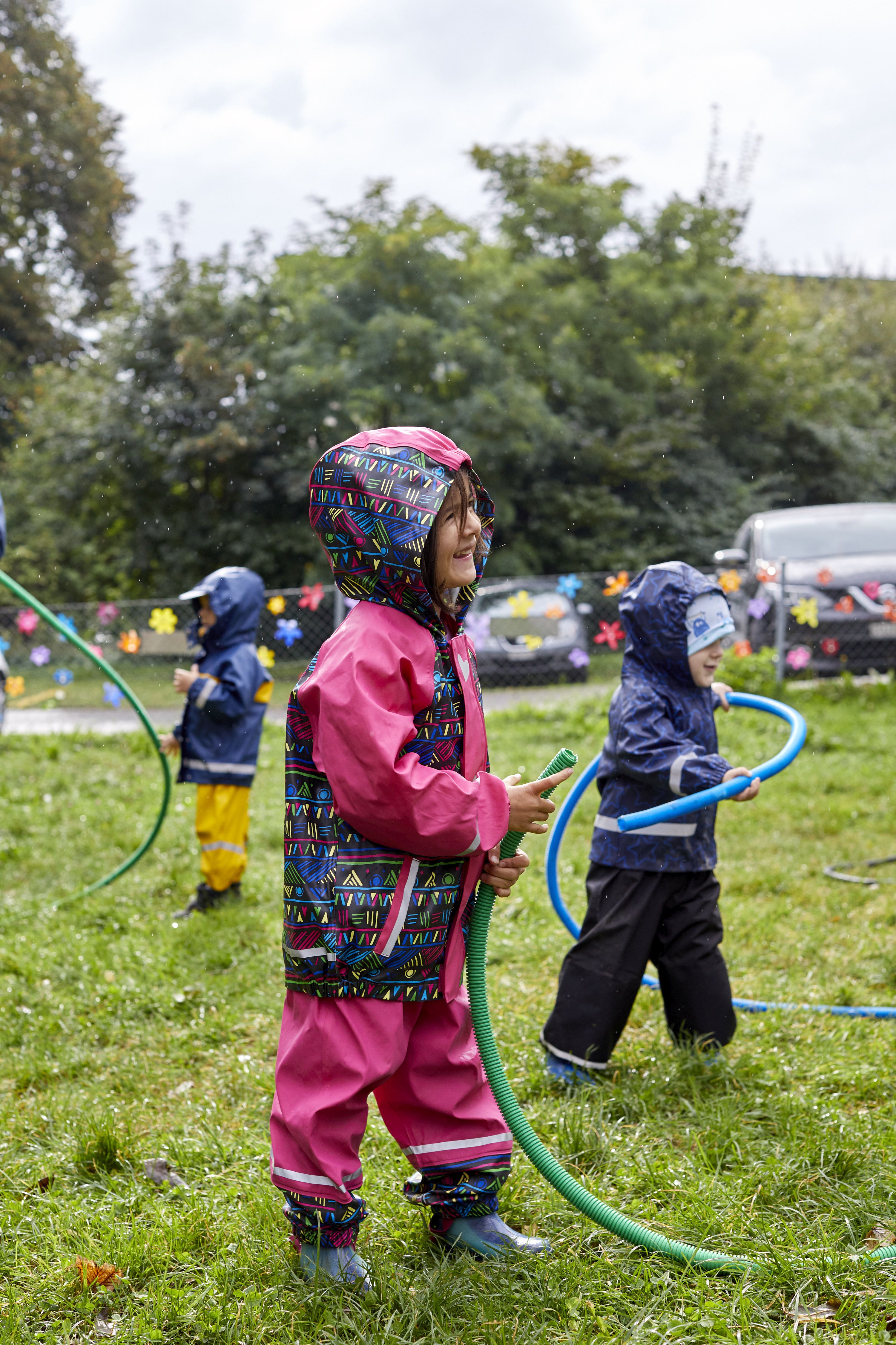 Kinder spielen mit Regenkleidung im Regen